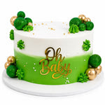A round birthday cake with a white and bright green gradient design, decorated with green and gold balloons, piped green frosting details, and gold 'Oh Baby' lettering on the front, set on a white round cake board. 3kg decorated white forest birthday cake from Cake Gurus Ruaka
