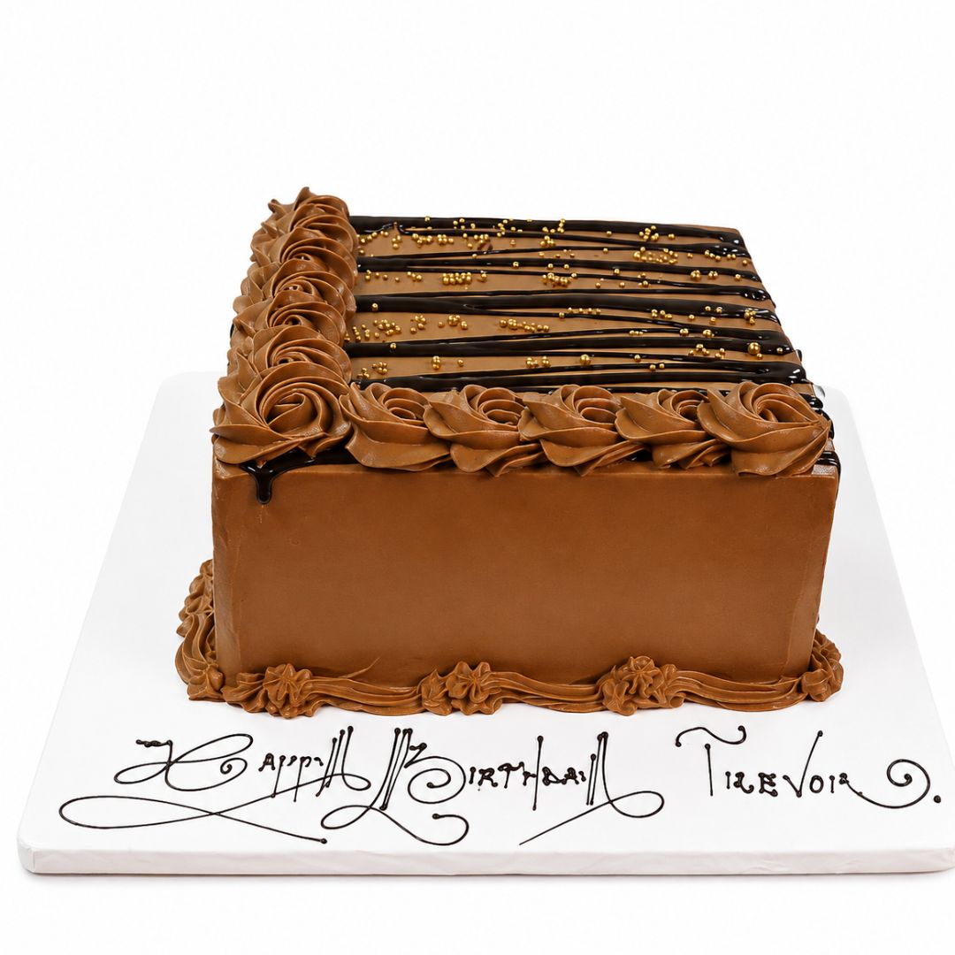 A rectangular birthday cake with smooth milk-chocolate brown frosting, piped rosette borders, and chocolate drizzle with gold sprinkles on top, presented on a white board with decorative script text. 1.5kg decorated Forest Fudge birthday cake from Cake Gurus Ruaka