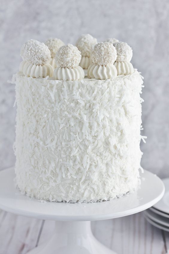 A Cinnamon frosted cake with white icing and coconut covered cherries on top,  as a sweet treat by Cake Gurus Ruaka Nairobi with deliveries in Nairobi and its environs.