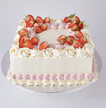 A round Fruit cake with white and pink icing, decorated with sliced strawberries on top  as a sweet treat by Cake Gurus Ruaka Nairobi with deliveries in Nairobi and its environs.