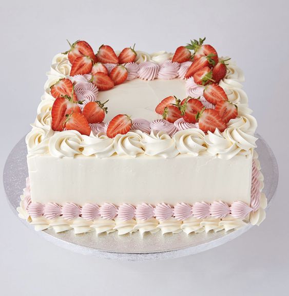 A round Fruit cake with white and pink icing, decorated with sliced strawberries on top  as a sweet treat by Cake Gurus Ruaka Nairobi with deliveries in Nairobi and its environs.