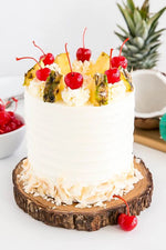 A Piña Colada Cake decorated with pineapple pieces and cherries,  as a sweet treat by Cake Gurus Ruaka Nairobi with deliveries in Nairobi and its environs.