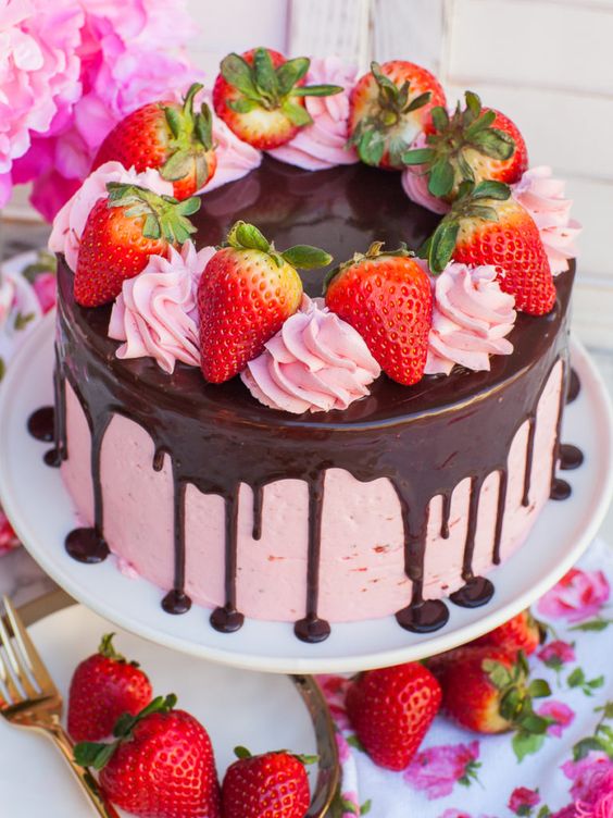 A decorated Strawberry Cake with pink layers, covered with a chocolate drip and topped with fresh strawberries and whipped cream  as a sweet treat by Cake Gurus Ruaka Nairobi with deliveries in Nairobi and its environs.