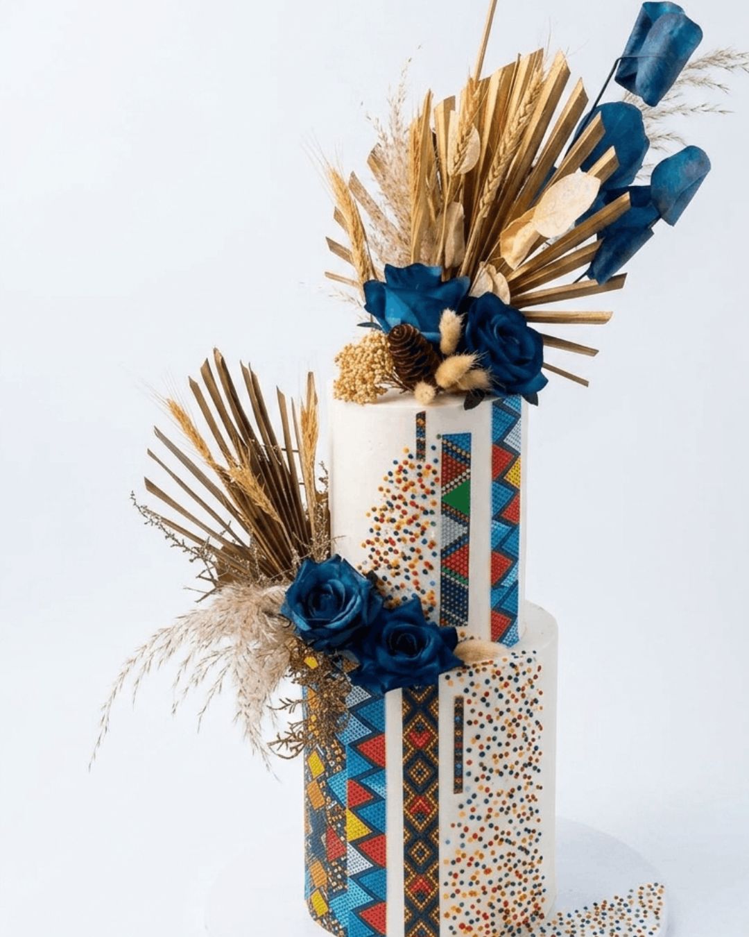 Decorative vase with blue flowers, gold leaves, and a colorful geometric pattern on a white background