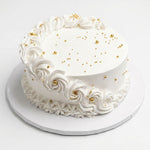 A round white Vanilla cake decorated with piped rosettes around the sides, scattered gold sprinkles on top, and a white round board underneath, photographed on a clean white background. Cake Gurus Same Day delivery. Ruaka, Nairobi. 