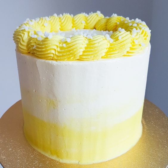 A round carrot cake with white and yellow layered frosting,  as a sweet treat by Cake Gurus Ruaka Nairobi with deliveries in Nairobi and its environs.