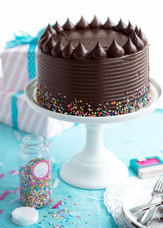 A chocolate mud cake with chocolate frosting and multicolored sprinkles on the bottom rim,  as a sweet treat by Cake Gurus Ruaka Nairobi with deliveries in Nairobi and its environs